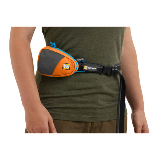Shown waist-worn, the Ruffwear Stash Bag™ pick-up bag / poo bag storage and dispensing system. Poppy Orange.